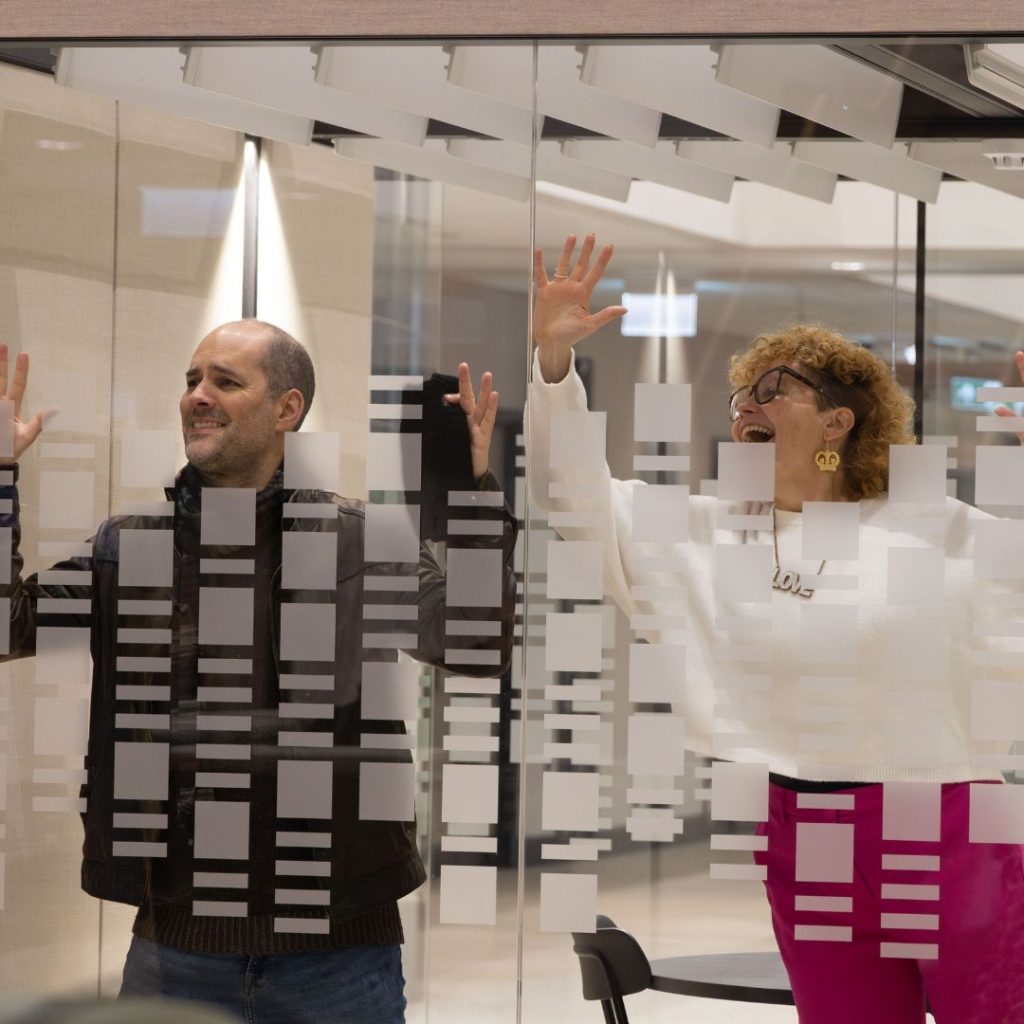 Two people trying to get noticed behind a glass wall.